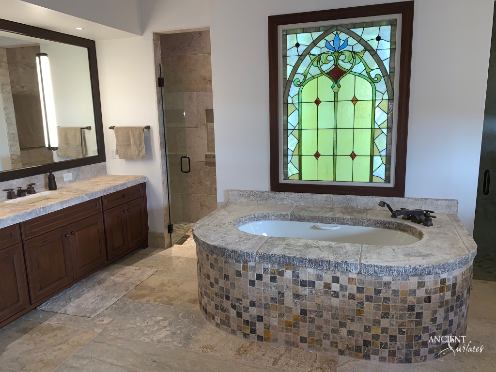 Luxury bathing captured in a rustic limestone bathtub by Ancient Surfaces, creating a cozy and inviting atmosphere, and serving as a testament to the company's commitment to preserving the beauty of ancient surfaces and transforming spaces.